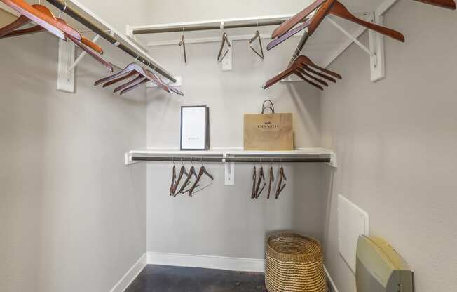 a walk in closet with a bench and hangers for gardening tools