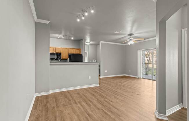 A spacious room with wooden flooring and a ceiling fan.