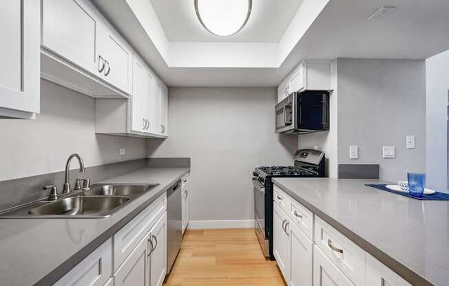 A kitchen with a sink, stove, and microwave.