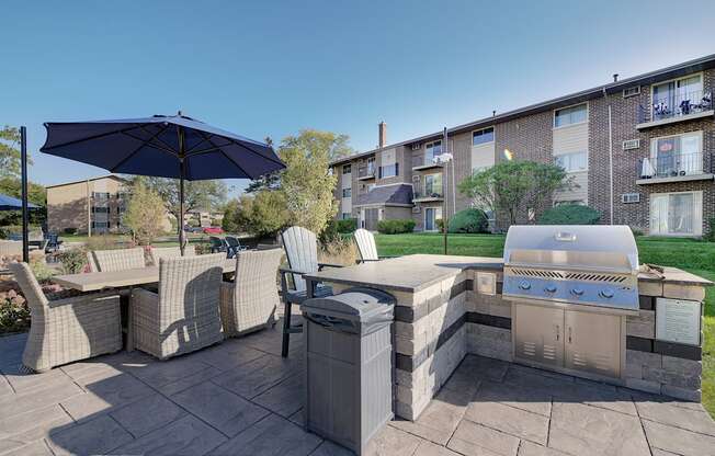 a backyard with an outdoor grill and table with chairs and an umbrella