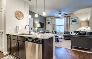 an open kitchen and living room with a couch and a ceiling fan