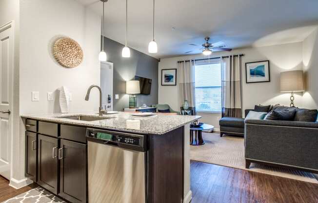 an open kitchen and living room with a couch and a ceiling fan