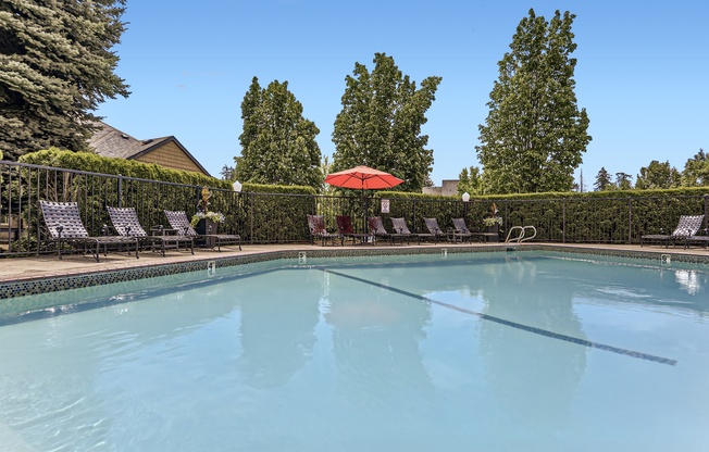 a swimming pool with chairs and an umbrella on the side of it