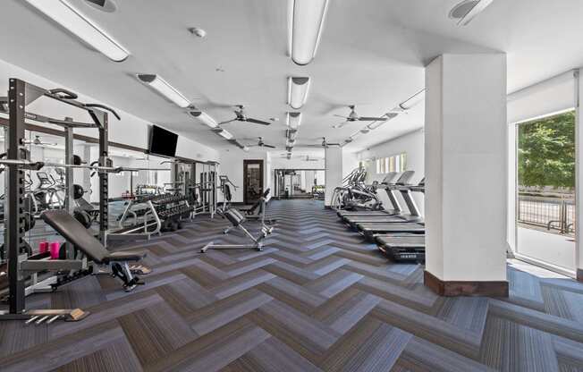 a gym with weights and cardio equipment on a wooden floor