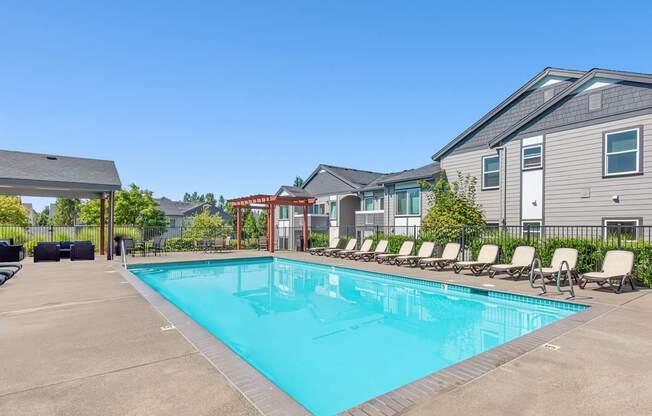 A swimming pool surrounded by lounge chairs and buildings in the background at The Landing Apartments and Townhomes, Oregon, 97045