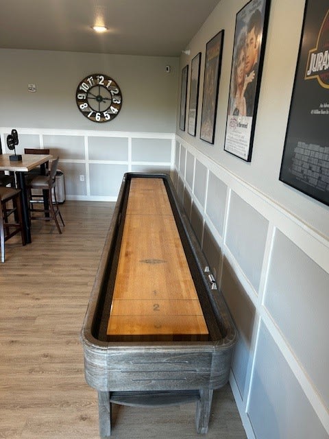 a shuffleboard table in a room with a clock on the wall