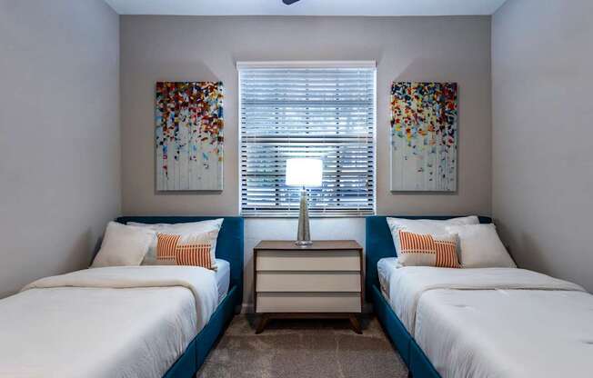 A bedroom with two beds and a nightstand.