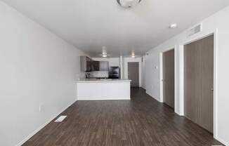 A spacious room with wooden flooring and white walls.