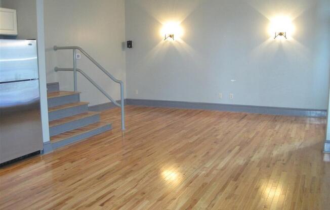 a large room with a wooden floor and stairs at East 4th Street, Cleveland, Ohio