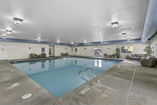 a swimming pool with chairs and tables around it  at Camelot Apartment Homes, Everett, WA, 98204