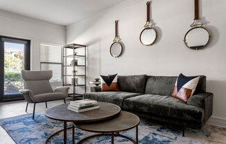 A living room with a grey couch, a grey chair, a coffee table, and a book on it.