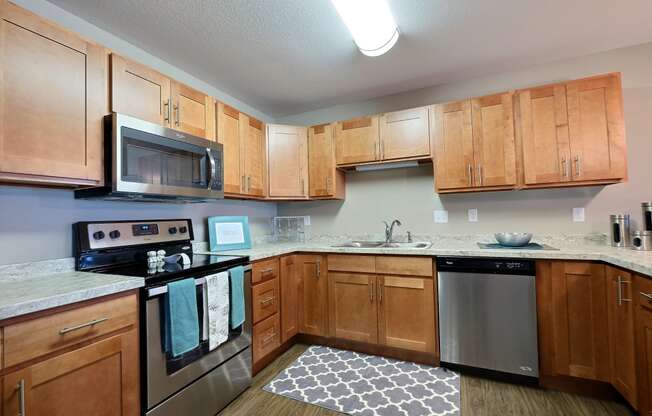 an empty kitchen with wooden cabinets and stainless steel appliances. Fargo, ND Urban Plains Apartments