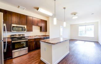 kitchen with island, stainless steel appliances and hardwood flooring at archer park apartments in southeast Washington dc