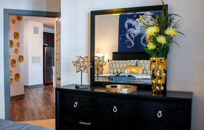 a bedroom with a black dresser with a large mirror and a bed
