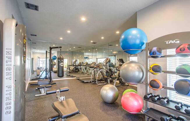 A gym with a variety of equipment including weights and exercise balls.