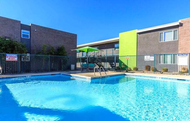 A swimming pool in front of a building with a green awning.