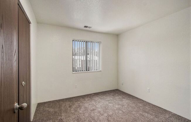 the living room of an empty home with a window and carpet