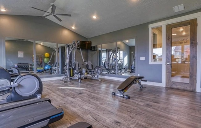 a gym with weights and cardio equipment and a glass door