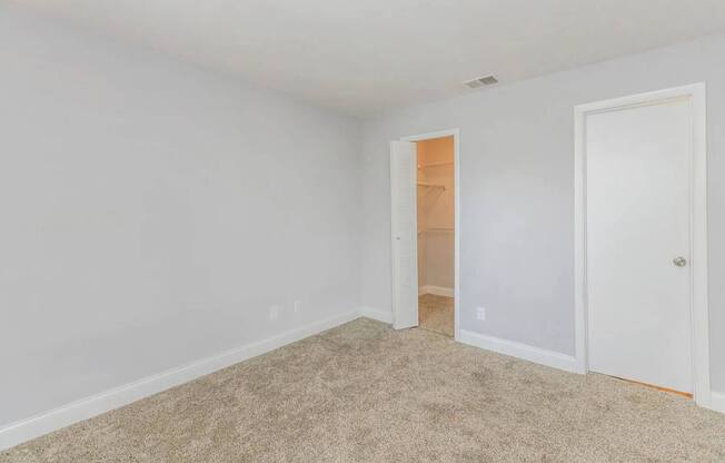 A room with a carpeted floor and two doors.