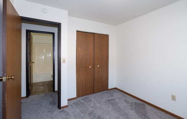 an empty room with a closet and a door to a bathroom. Fargo, ND Pacific South Apartments