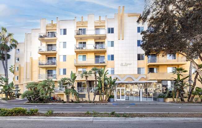 A large white building with a yellow stripe on the side and balconies on the second floor.