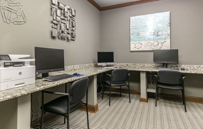 three desks with computers and chairs in a room