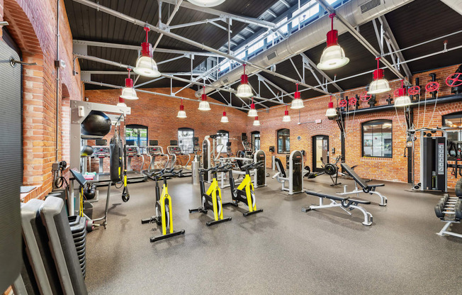 a gym with weights and cardio equipment and brick walls at The Tannery, Connecticut