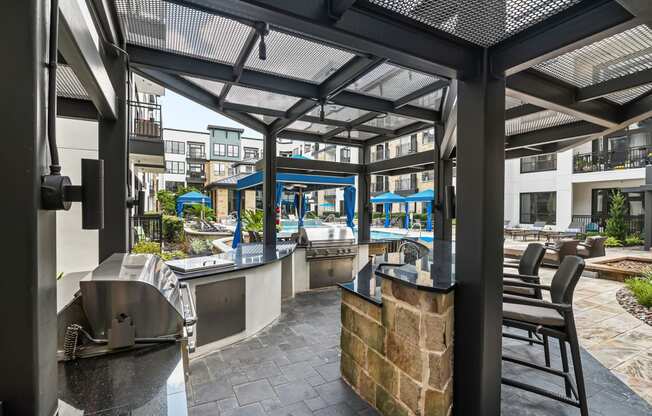 a patio with a bar and tables and a pool