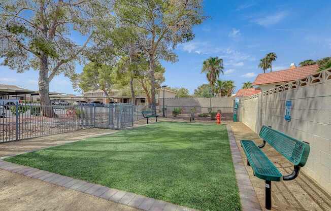 A park with a green bench and a fence.