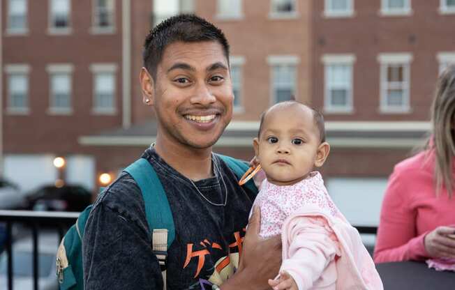 a man holding a baby and smiling at the camera