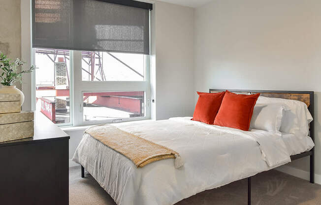 A bedroom with a large bed and a window overlooking a construction site.