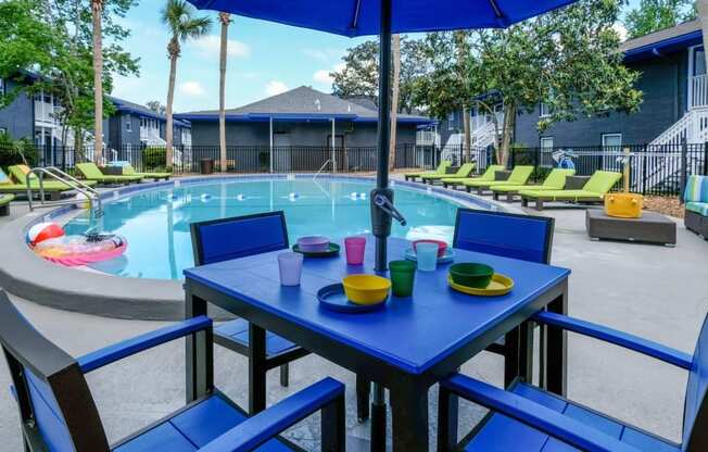 Jacksonville, FL Apartments for Rent - Mandarin Bay - Outdoor Dining Area with Umbrella Next to the Sparkling Swimming Pool Surrounded By Lounge Chairs