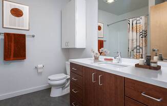 A bathroom with a toilet, sink, and cabinets.