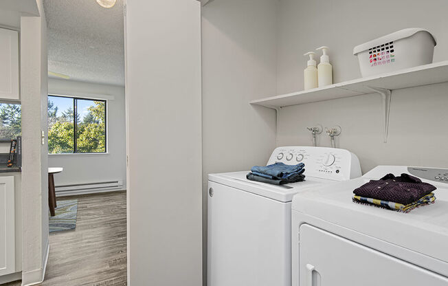a white laundry room with a washer and dryer and a window