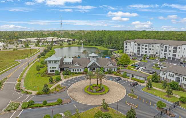 an aerial view of an apartment complex with a pond and parking lot