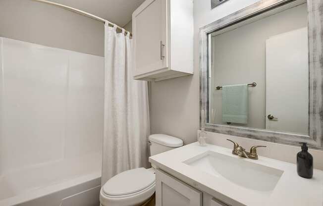 a bathroom with a white sink and toilet and a white shower curtain