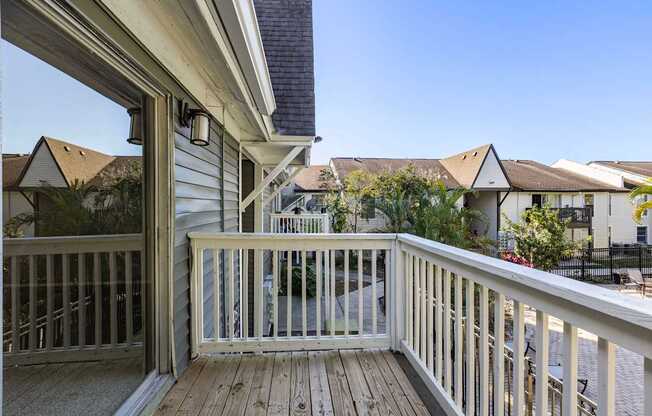 A wooden deck with a railing and a view of a residential area.