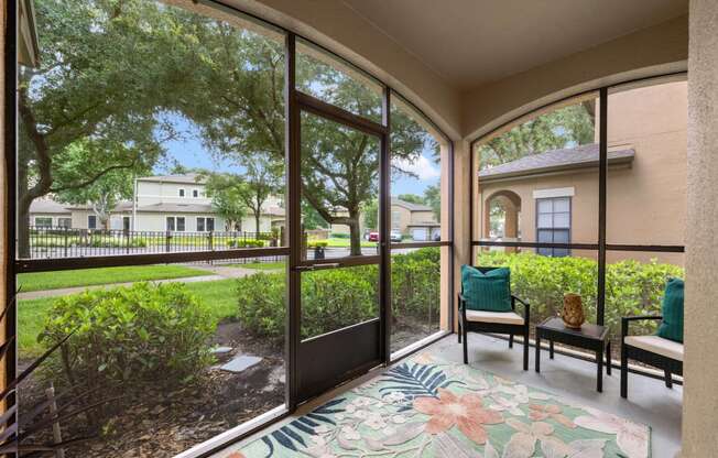 a patio with large windows and chairs and a rug