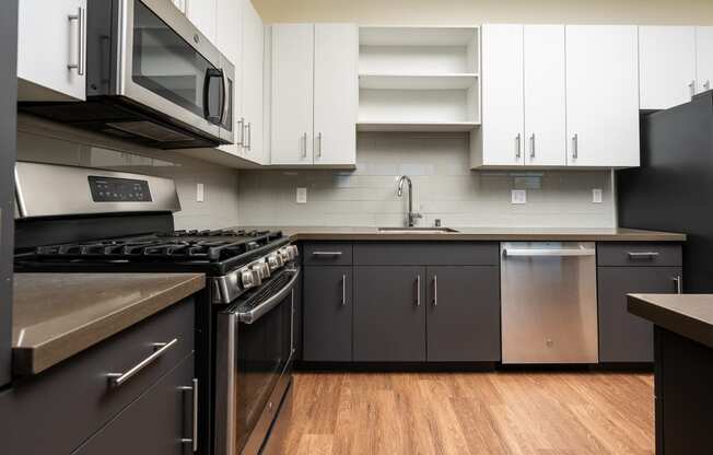 a kitchen with stainless steel appliances and white cabinets and dark bottom cabinets