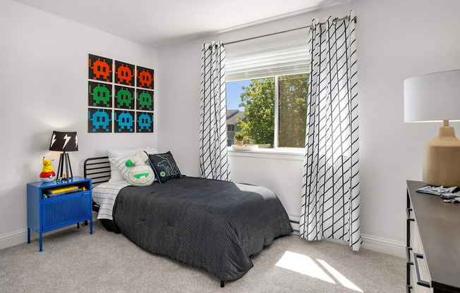 A bedroom with a bed, nightstand, and window with curtains.