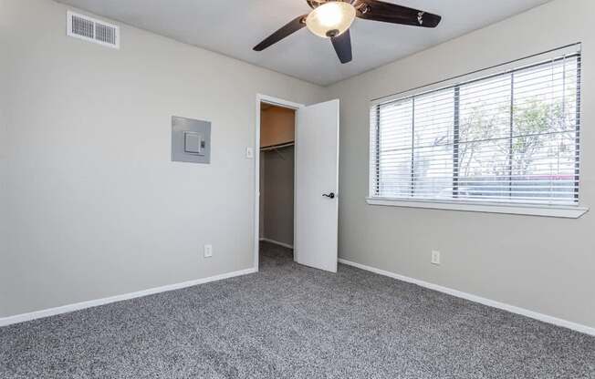 A room with a ceiling fan and a window with blinds.