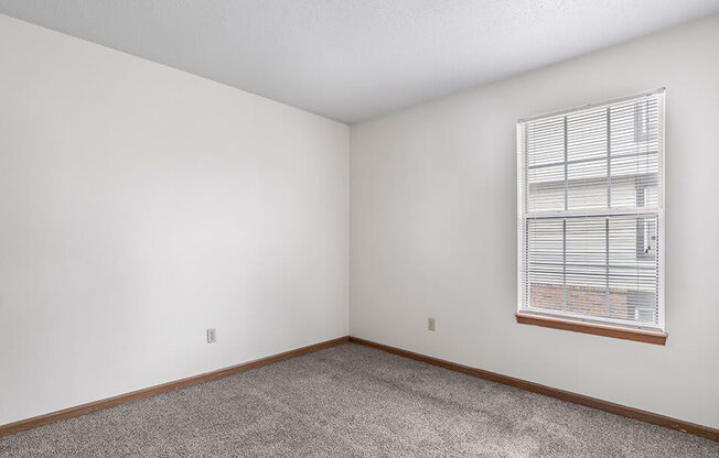 a bedroom with white walls and a window