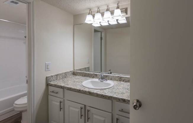 A bathroom with white vanity in a 2 bedroom, 2 bath with balcony apartment home at Harvard Square Apartments in the Vickery Midtown neighborhood of Dallas, TX.