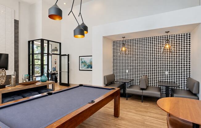 Pool table and seating beneath pendant lights in the resident lounge at Icon Avondale Apartments in Decatur, GA.