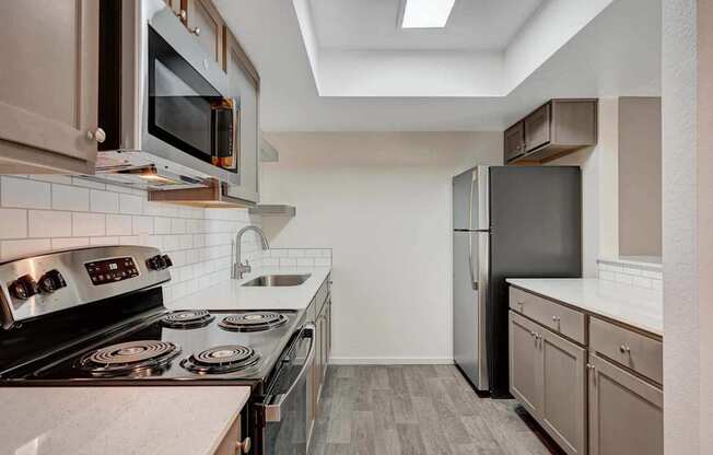 A kitchen with a black refrigerator and stove top oven.