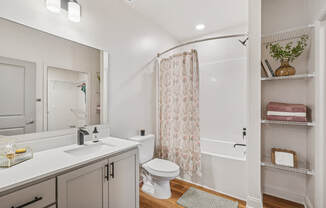 A white bathroom with a toilet, sink, and shower.