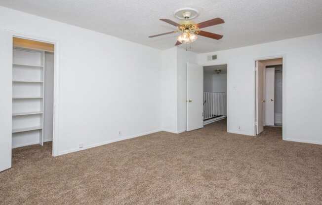 an empty living room with a ceiling fan