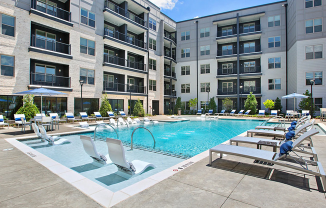 The pool area at our apartments in Atlanta, featuring pool chairs, beach chairs, and a view of the apartments.