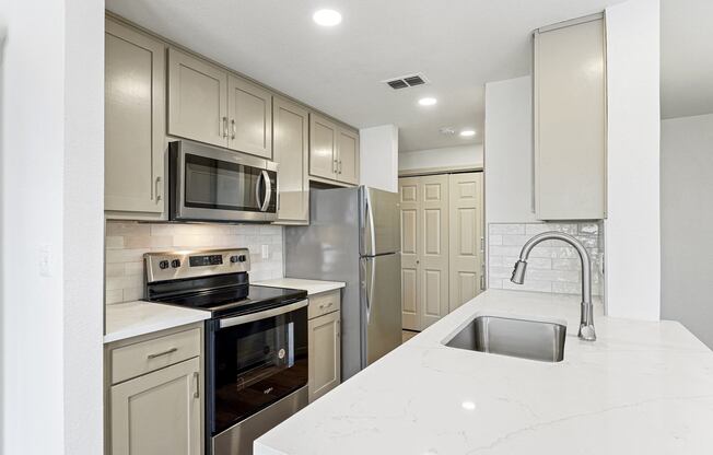 a white kitchen with stainless steel appliances and white counter tops at The Legends at Eagle Mountain Lake, Fort Worth, Texas