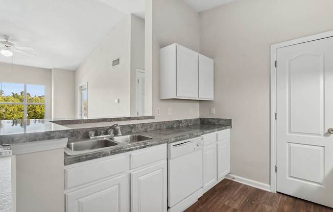 A kitchen with white cabinets and a marble countertop.